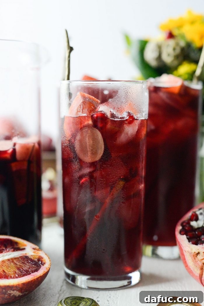 Partially full glass of Pomegranate Sparkling Apple Cider Sangria on a table