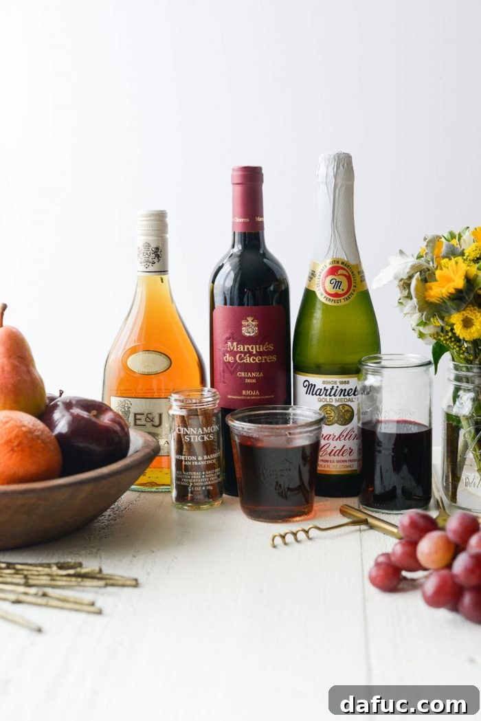 Ruby Fizz Sangria 4 Ingredients for Pomegranate Sparkling Apple Cider Sangria laid out on a table