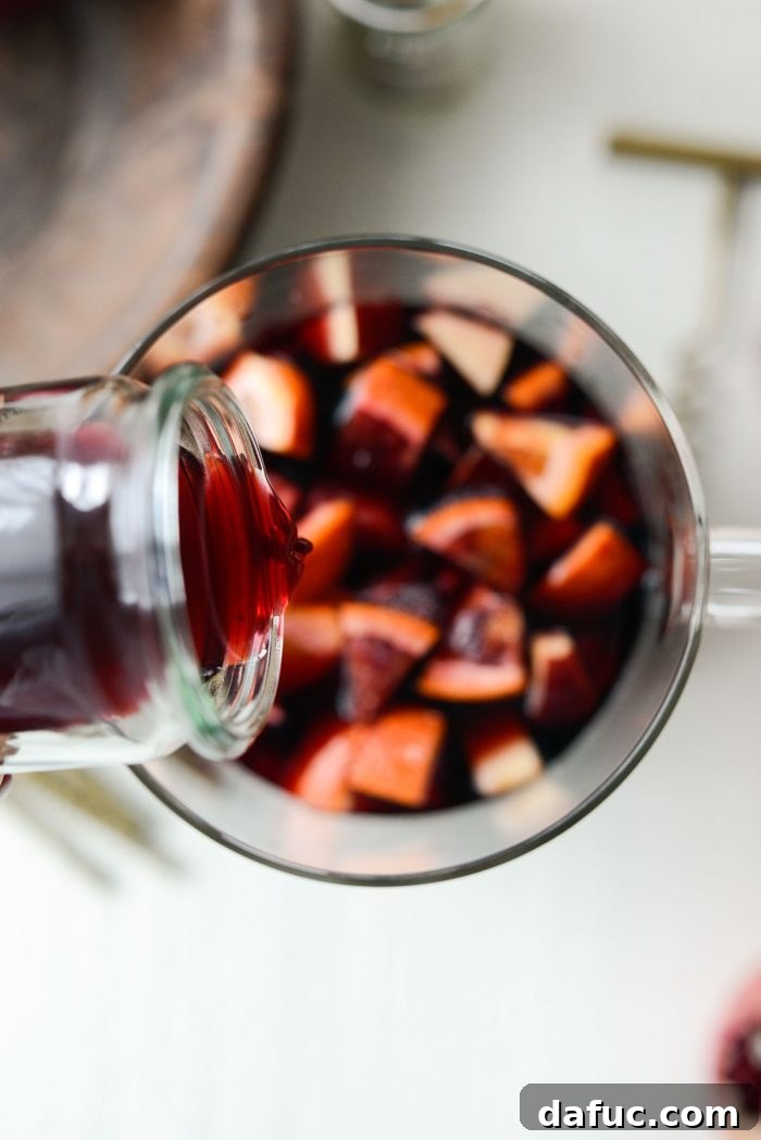 Ruby Fizz Sangria 10 Pouring pomegranate juice into the sangria pitcher