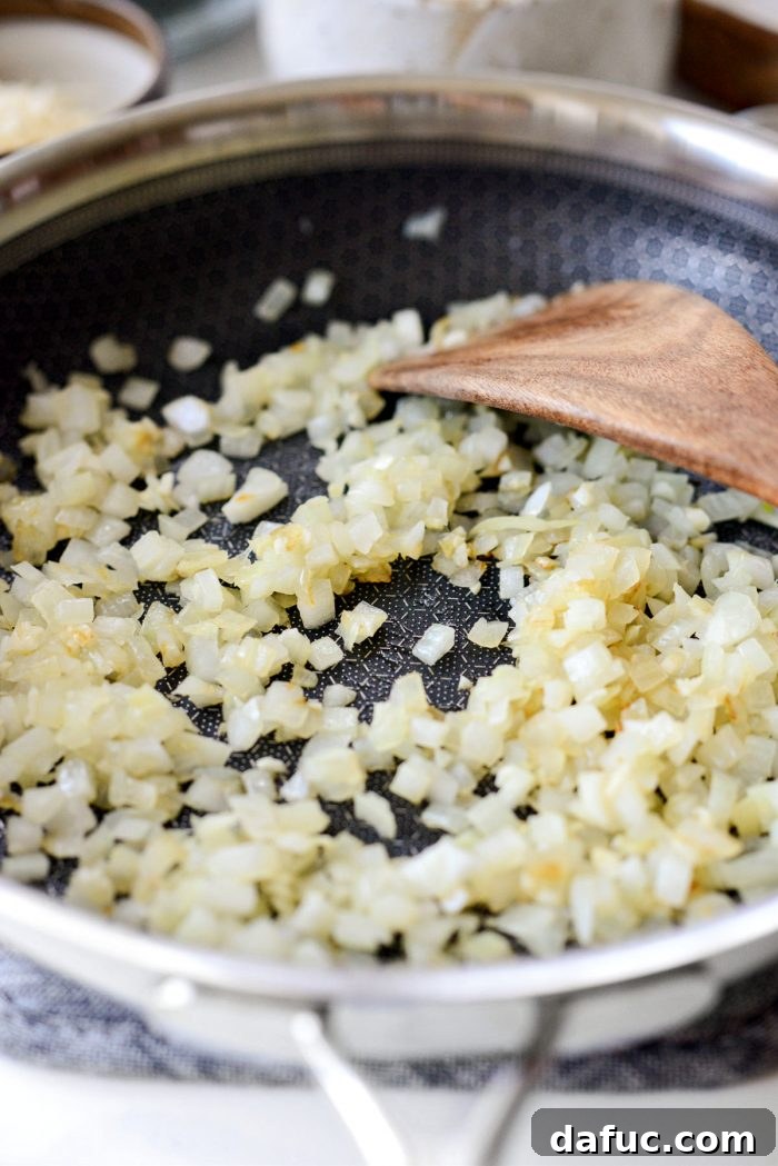 Finely diced onions and minced garlic sautéing in a skillet until translucent and fragrant.