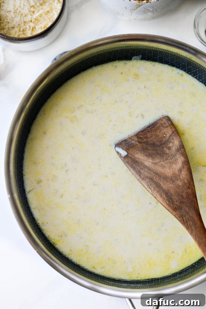 The creamy sauce in the skillet being seasoned with kosher salt, black pepper, and freshly grated nutmeg, ready to be stirred.