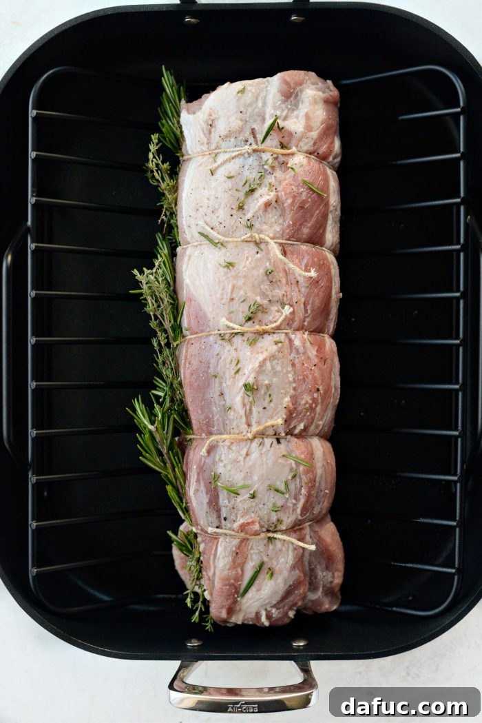 Sweet Pear, Savory Bacon, and Tangy Blue Cheese Stuffed Pork Loin 14 Tied pork loin resting on a roasting rack in a pan