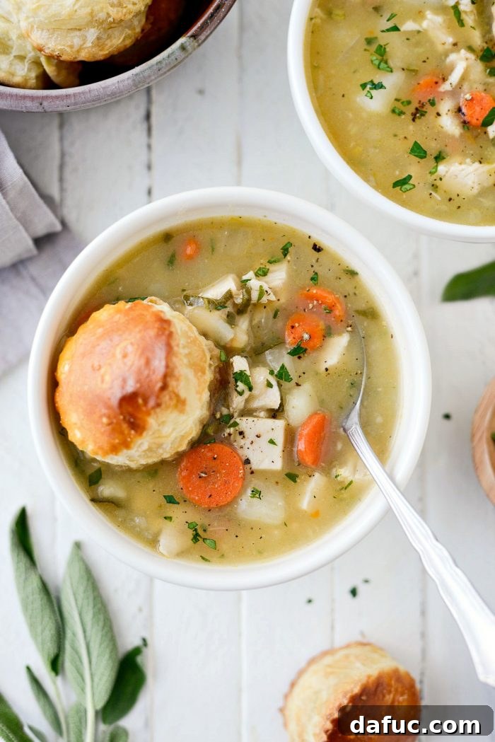 A rustic, steaming bowl of Homemade Turkey Pot Pie Soup, showcasing a rich, creamy texture achieved without heavy cream, packed with turkey and garden vegetables.