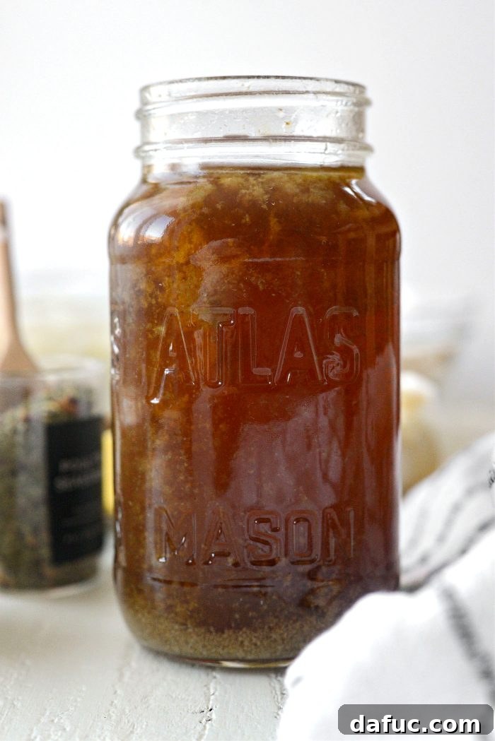 A clear glass pot of simmering homemade turkey stock, rich golden brown, with turkey bones, aromatic vegetables, and herbs, perfect for future culinary uses.