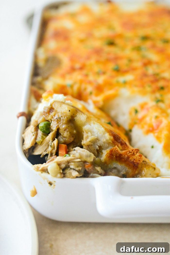 A golden-brown Leftover Turkey Shepherd’s Pie, featuring a rich turkey and vegetable filling beneath a savory layer of stuffing, mashed potatoes, and melted cheese.