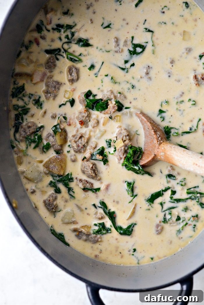 A cook stirring a large pot of Zuppa Toscana soup.