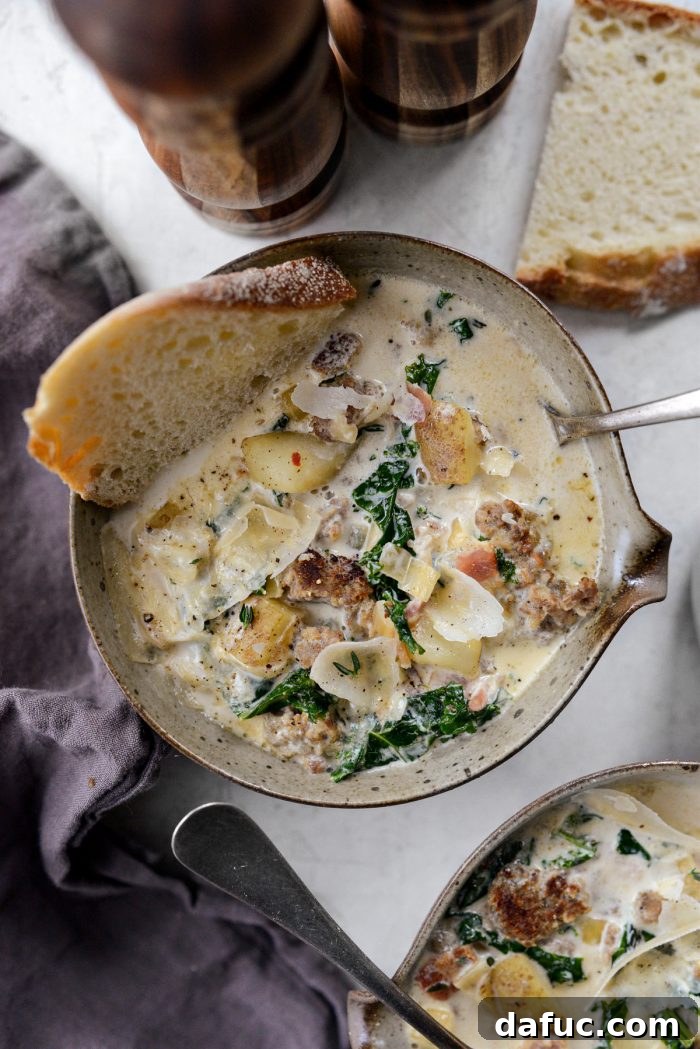 A rustic bowl of Zuppa Toscana with crusty bread and a napkin, suggesting a comforting meal.