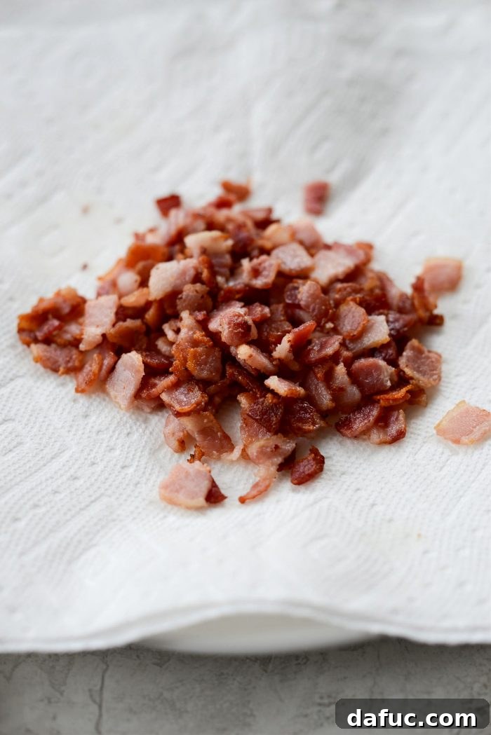 Crispy bacon bits resting on a paper towel-lined plate, ready to be added back later.