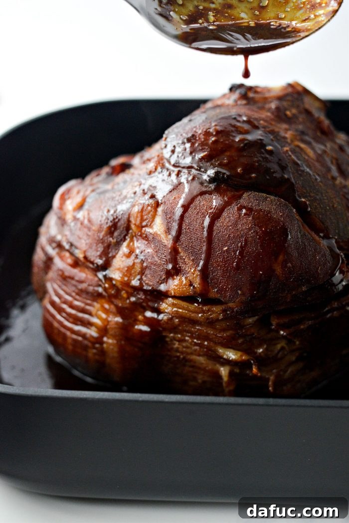 Jeweled Pomegranate Bourbon Glazed Ham 15 A spoon scooping up the caramelized glaze from the bottom of the roasting pan and spooning it back over the ham for re-glazing.