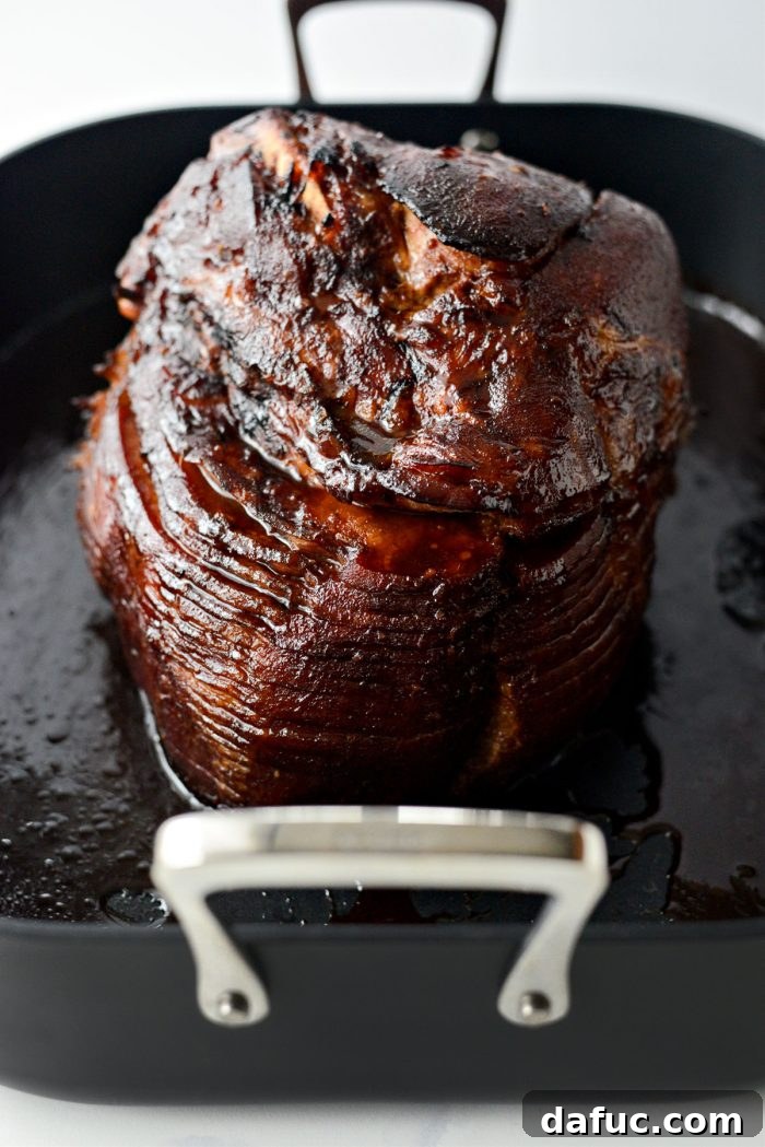 Jeweled Pomegranate Bourbon Glazed Ham 17 A close-up of the Pomegranate Bourbon Glazed Ham, with a final spoonful of glaze being added, highlighting its rich color and texture.