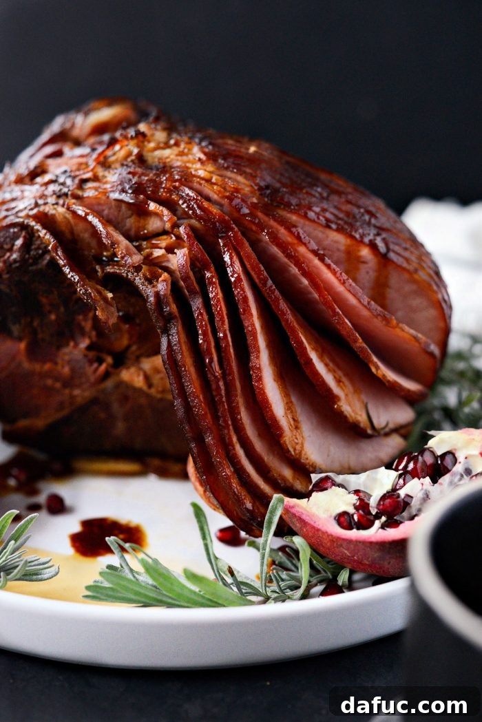 Jeweled Pomegranate Bourbon Glazed Ham 3 Close-up view of the Pomegranate Bourbon Glazed Ham, showing its sticky, caramelized glaze and juicy interior, with extra glaze pooled at the bottom.