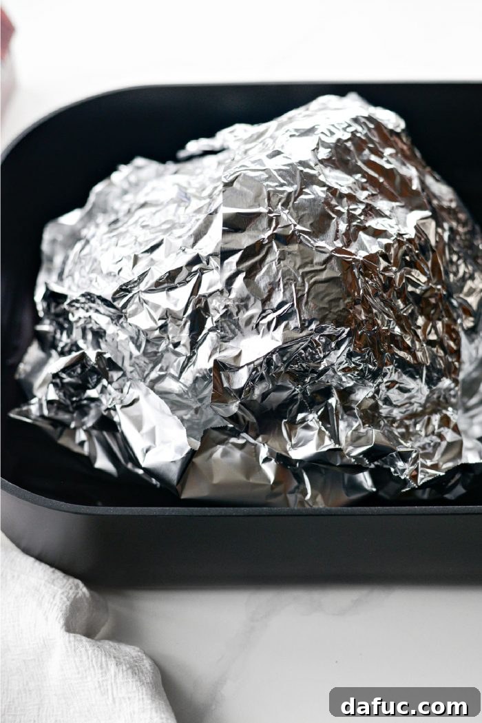Jeweled Pomegranate Bourbon Glazed Ham 7 The roasting pan with the ham covered tightly with aluminum foil, ready to be placed in the oven.