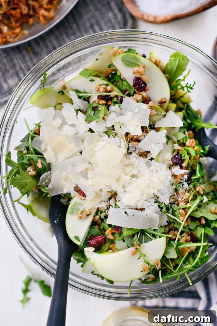 Shaved Parmesan cheese being gently added to the assembled winter farro salad, enhancing its savory notes.