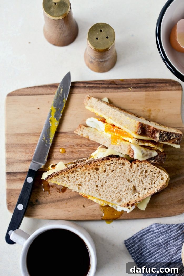 Two halves of the ultimate cheesy fried egg sandwich, revealing the golden yolk and melted cheese, ready to be savored as a perfect handheld meal.
