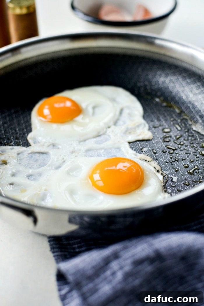 A pan being sprayed with olive oil, preparing for the eggs to be cooked. This healthy approach reduces excess fat while ensuring non-stick cooking.
