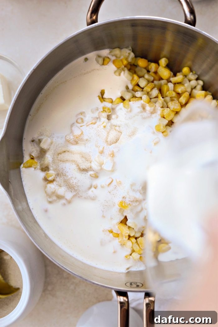 Golden Garlic Parmesan Corn Gratin 7 Pouring heavy whipping cream into the saucepan with corn