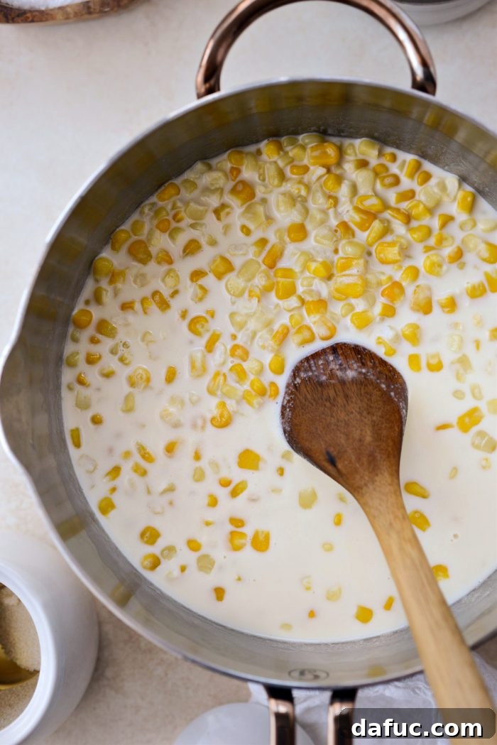 Golden Garlic Parmesan Corn Gratin 9 Corn and cream mixture simmering in a saucepan
