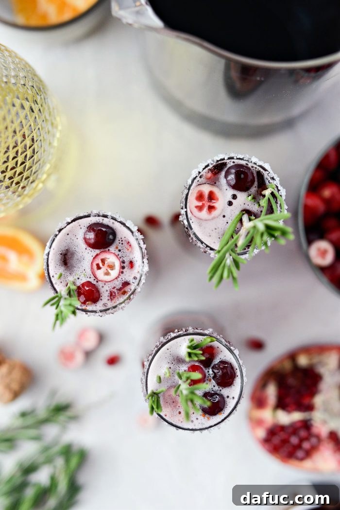 Bright & Bubbly Christmas Mornings 3 Two glasses of Christmas Morning Mimosas by Simply Scratch, showing the vibrant red hue and festive garnishes