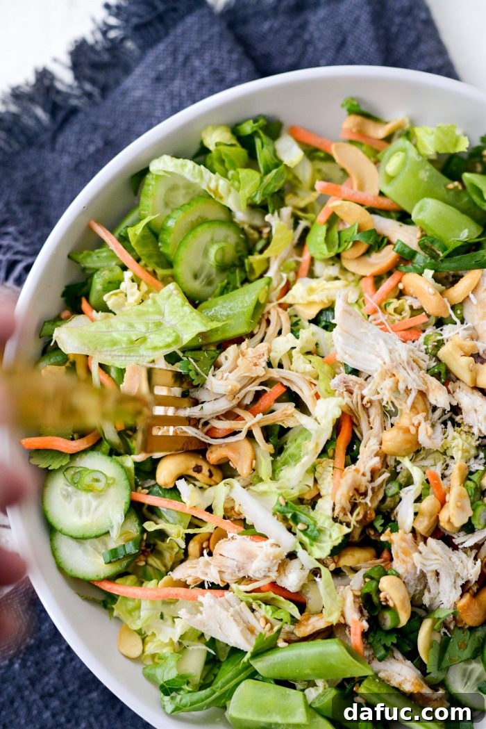 A beautifully plated Asian Cashew Chicken Mason Jar Salad with a gold fork.