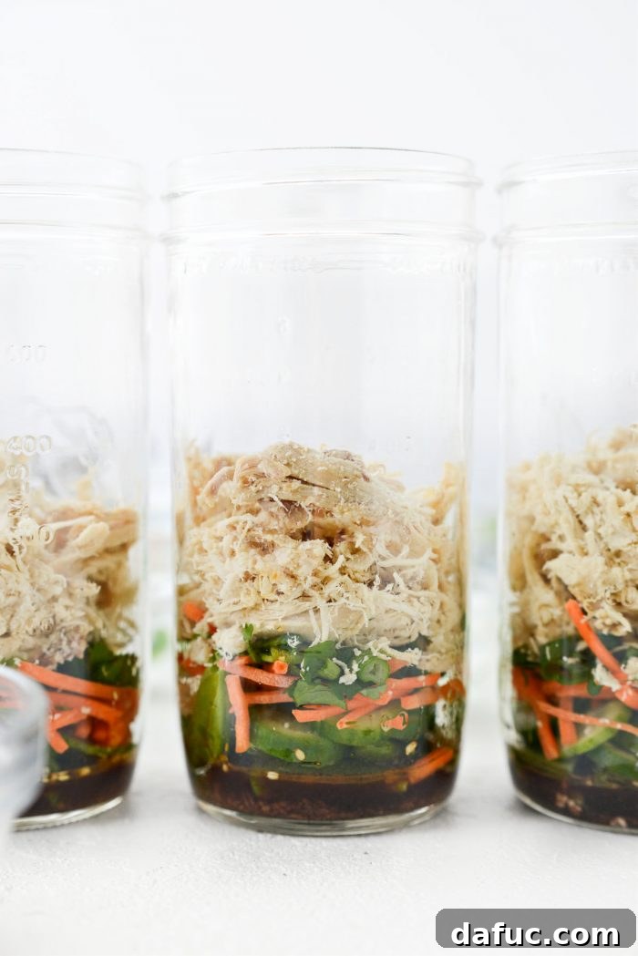 Mason jar with cilantro, green onion, and shredded cooked chicken added as the next layer.