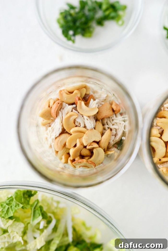 Measuring and adding lightly salted cashews to the Asian Cashew Chicken Mason Jar Salad.
