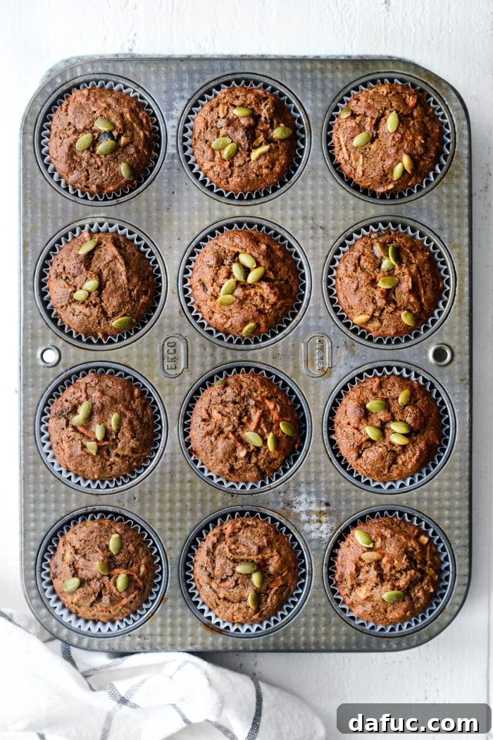 Freshly baked Morning Glory Muffins in a muffin tin, golden brown and puffed up.