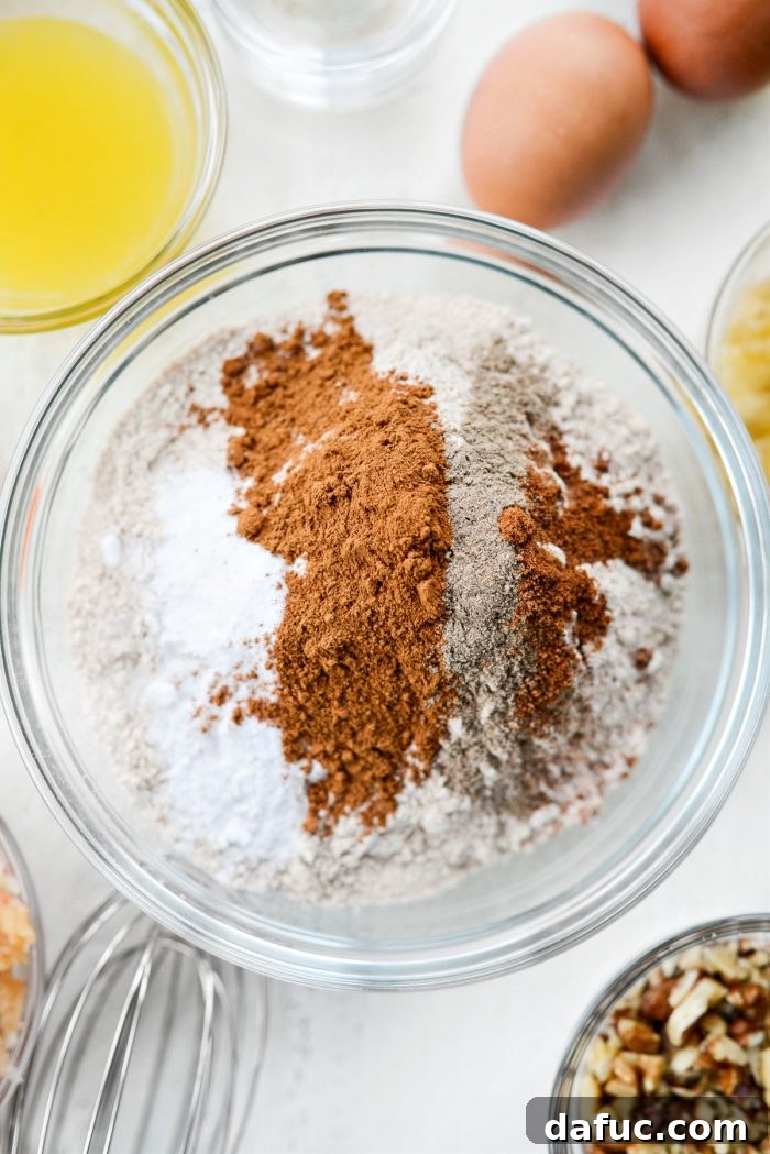 A bowl containing dry ingredients: whole wheat flour, baking soda, cinnamon, cardamom, nutmeg, and salt.