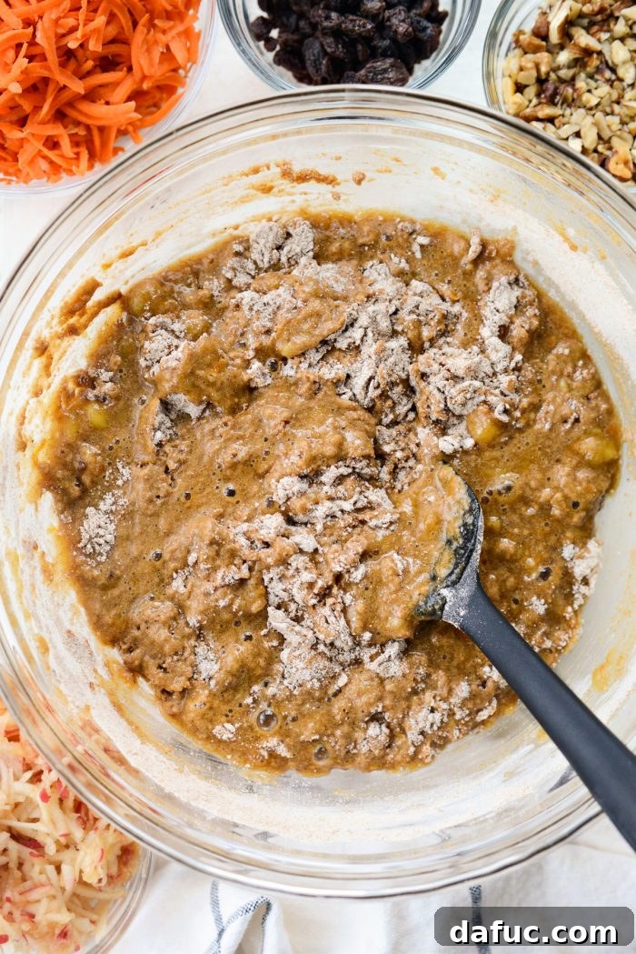 Dry ingredients partially mixed into wet ingredients in a large bowl, showing streaks of flour.