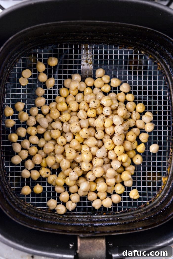 Perfectly Crisp Air-Fried Chickpeas 10 Chickpeas in an air fryer basket, sprayed with olive oil and seasoned with salt and pepper