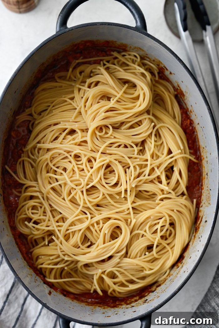 Slow Roasted Spaghetti Sauce 16 Cooked spaghetti being added directly into the slow baked sauce in a Dutch oven.