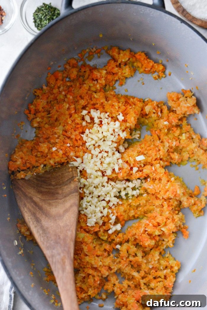 Slow Roasted Spaghetti Sauce 9 Minced garlic being added to the sautéed vegetables in a Dutch oven.
