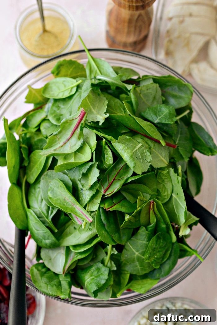 Adding a package of power greens to the mixing bowl with other salad ingredients
