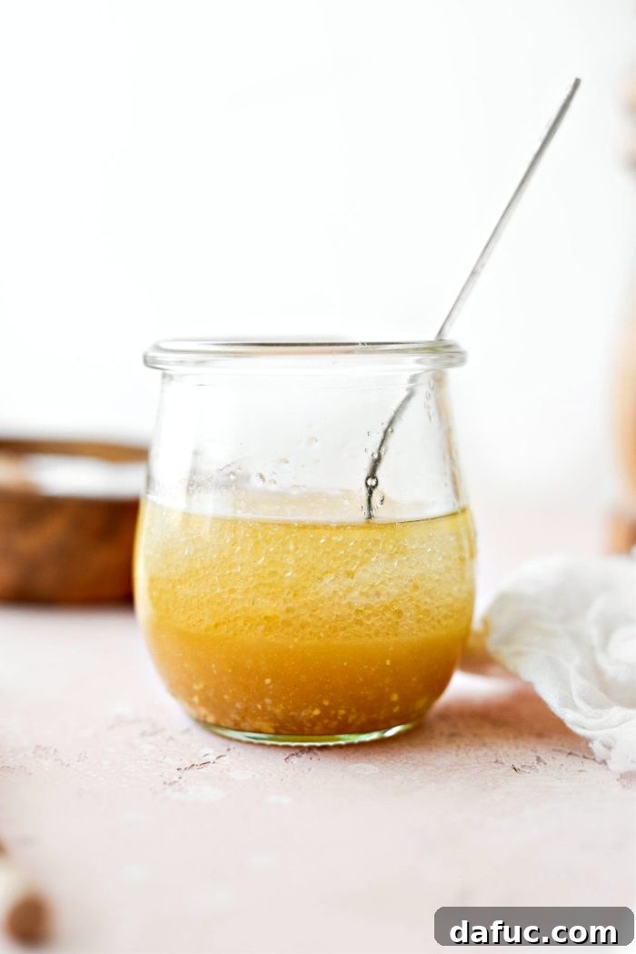 Whisking apple cider vinaigrette ingredients in a jar until well combined and emulsified