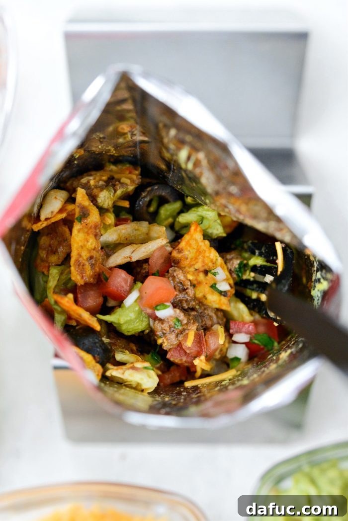 A fully assembled beef taco walking taco with Doritos and toppings, ready to eat.
