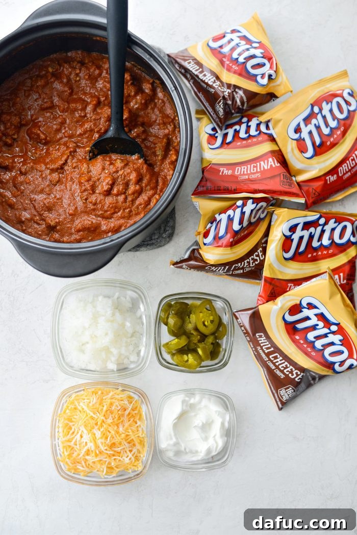 Walking Tacos Two Ways 15 Ingredients for chili cheese walking tacos including Fritos, chili, cheddar jack cheese, sour cream, pickled jalapeños, and minced white onion.