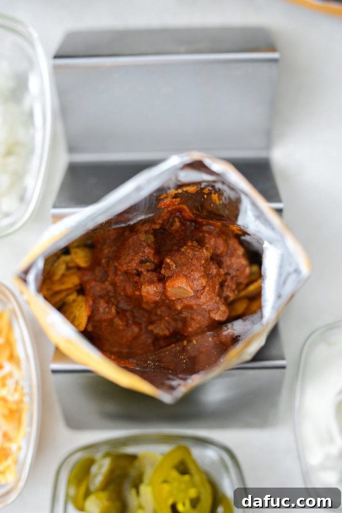 Walking Tacos Two Ways 18 No-bean chili being added to a bag of crushed Fritos.