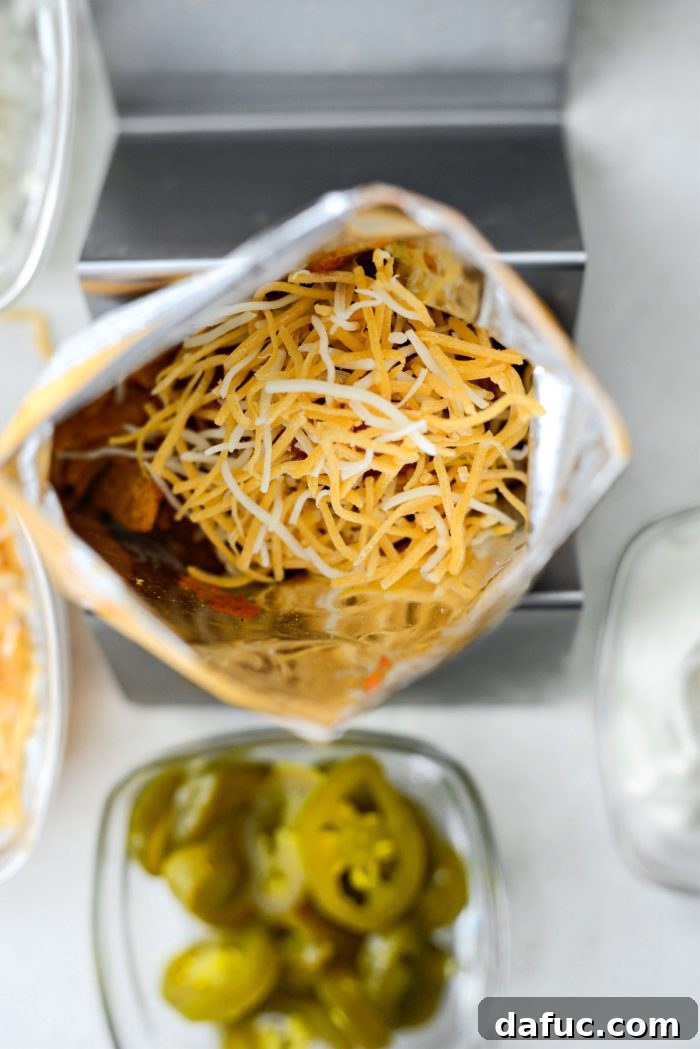 Walking Tacos Two Ways 19 Shredded cheddar jack cheese being added on top of the chili in the Fritos bag.