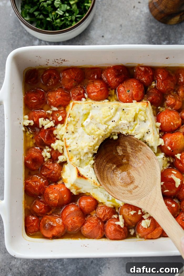 Blistered Tomato Feta Pasta 15 Mixing baked feta cheese with burst cherry tomatoes in a baking dish