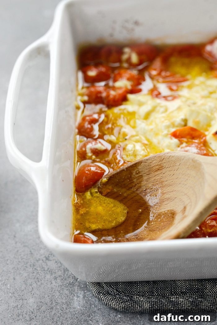 Blistered Tomato Feta Pasta 16 Pressing on burst tomatoes while mixing the baked feta pasta sauce