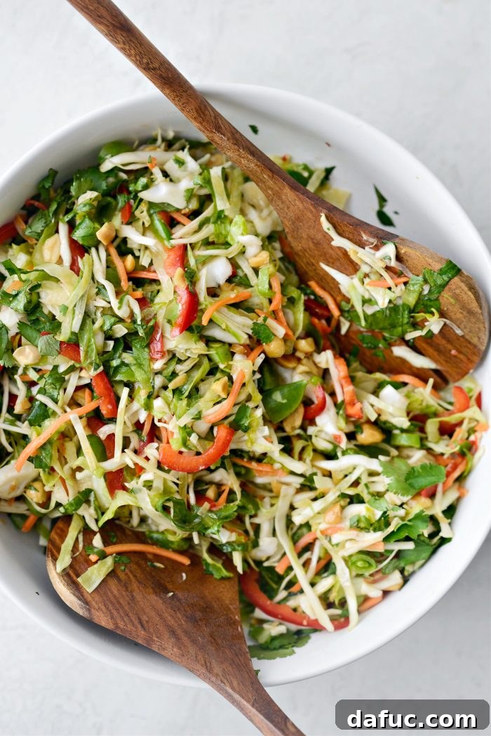 Zesty Thai Cabbage Slaw 12 Thai Cabbage Salad presented in a white bowl with wooden serving utensils.