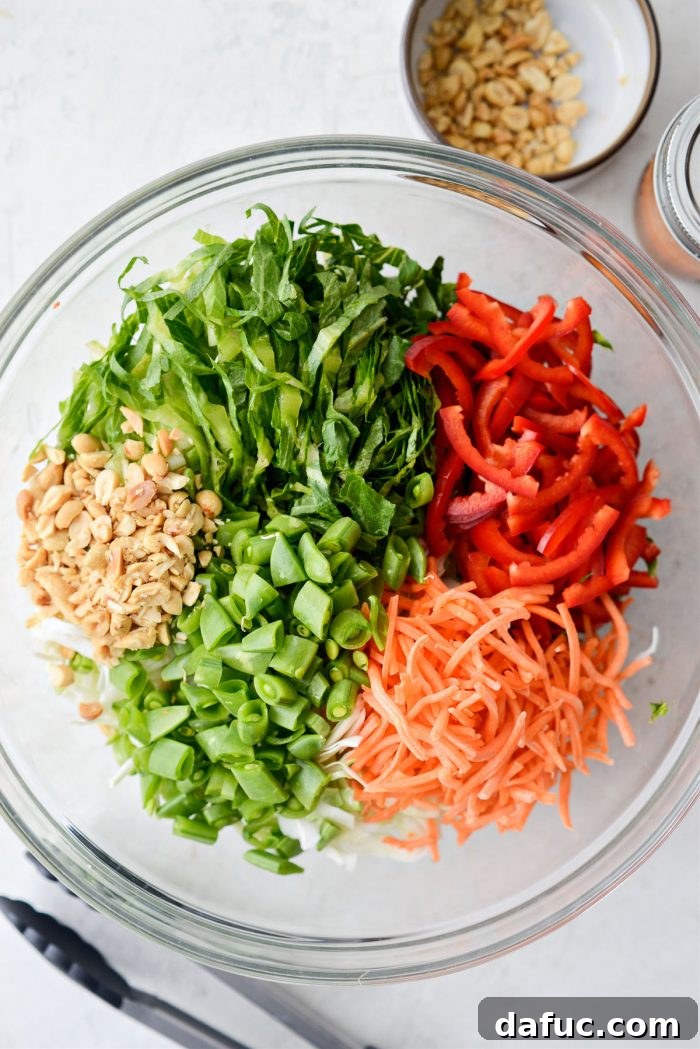 Zesty Thai Cabbage Slaw 7 Shredded cabbage, romaine, red pepper, carrots, and peanuts in a large mixing bowl.