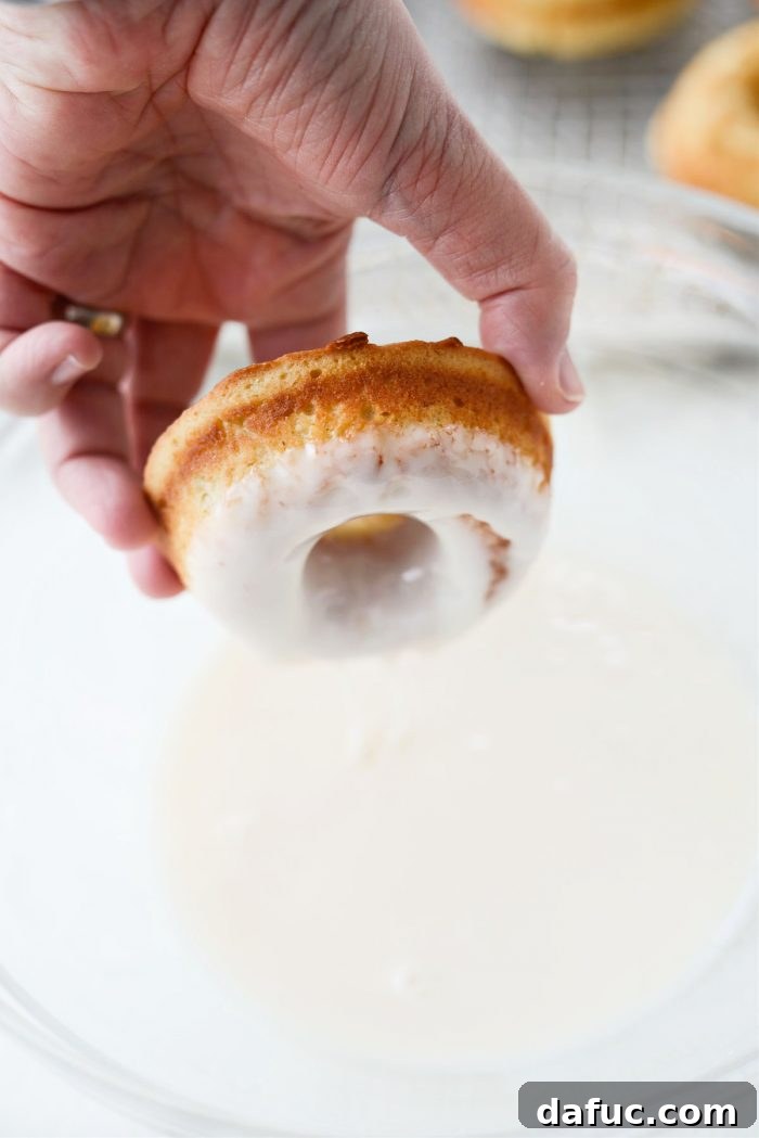 A freshly glazed Glazed Buttermilk Cake Doughnut on a wire rack, with the glaze still wet.