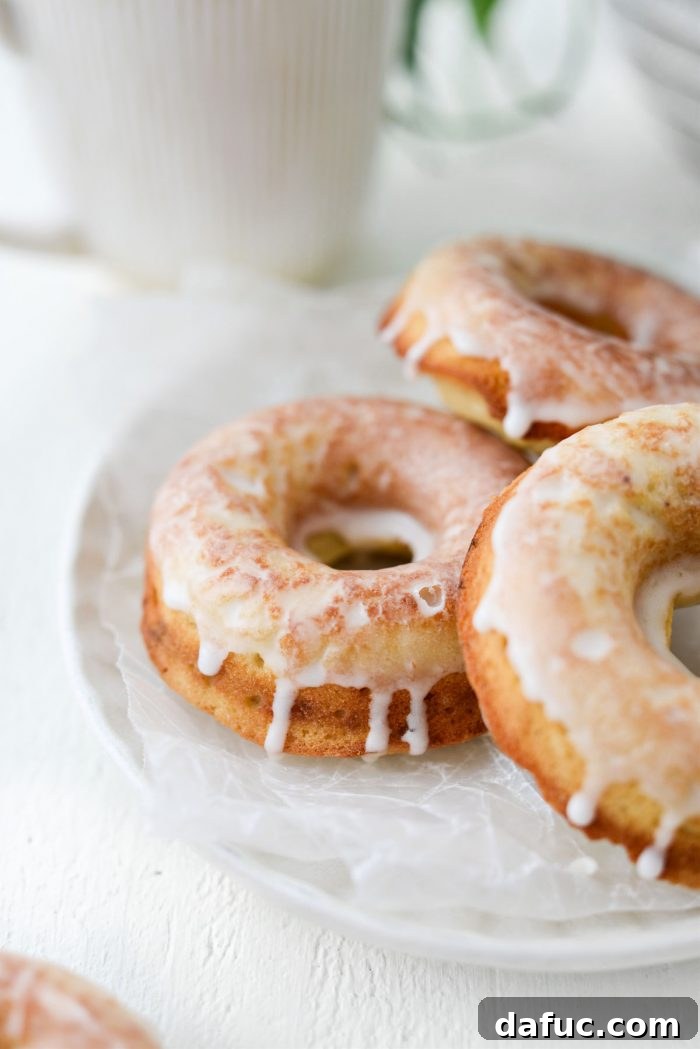 A visually appealing shot of several Glazed Buttermilk Cake Doughnuts on a plate, highlighting their appetizing appearance.