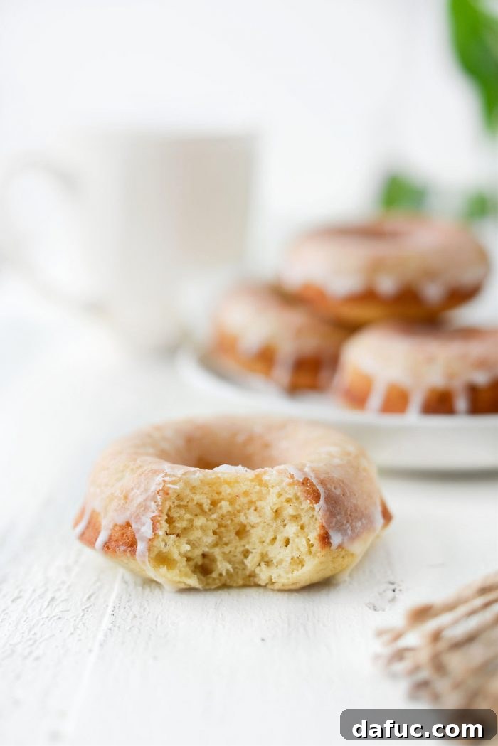 A cozy kitchen scene with a plate of Glazed Buttermilk Cake Doughnuts and a hot beverage, suggesting a relaxing treat.