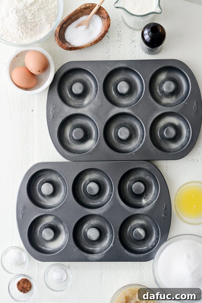 Doughnut pans being sprayed with nonstick cooking spray, ensuring easy release.