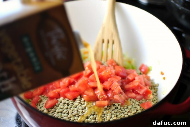 Vegetable broth being poured into the lentil soup