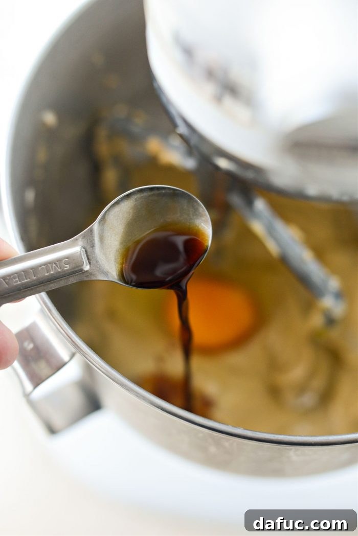 Vanilla extract being added with the last egg to the cake batter