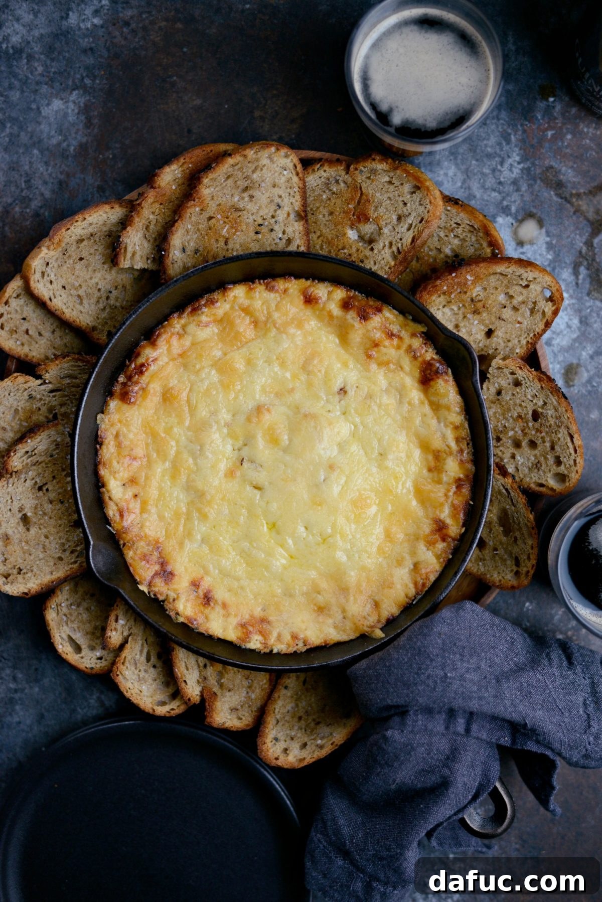 25+ Delicious St. Patrick's Day Recipes 15 Warm Guinness Dubliner Dip served with toasted rye bread slices on a wooden board