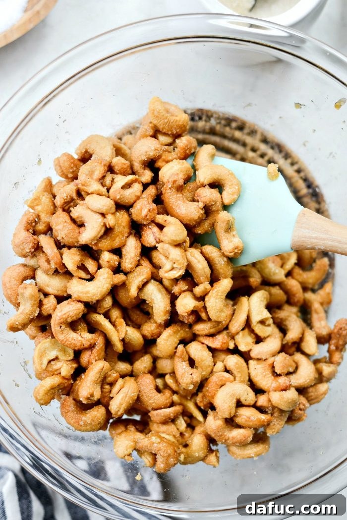 Decadent Honey Roasted Cashews 11 Transferring hot honey roasted cashews into a mixing bowl.