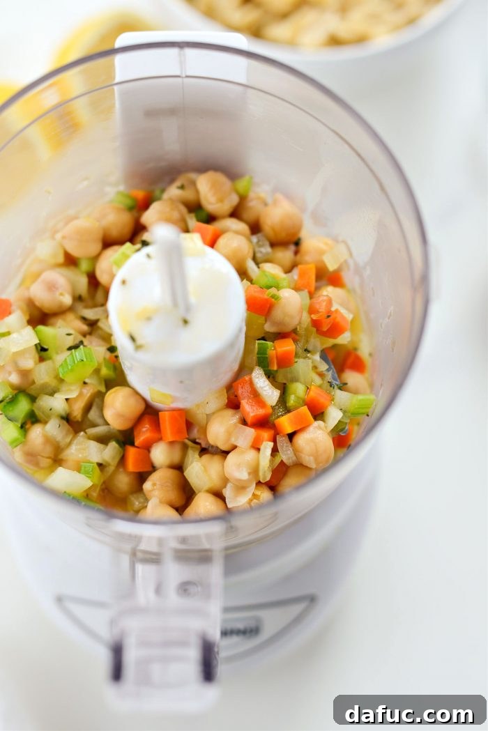 Sunshine Chickpea Bowl 11 Using a slotted spoon to carefully transfer a portion of chickpeas and vegetables from the simmering soup into a food processor for pureeing.